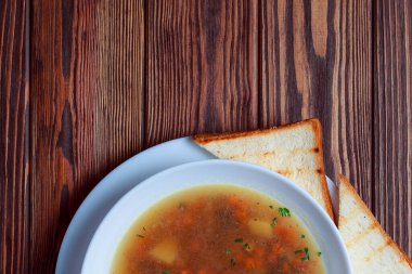 Tahta tepside ekmekle sebze çorbası. Koyu renk tahta arka planda beyaz kase. Üst Manzara. Boşluğu kopyala.