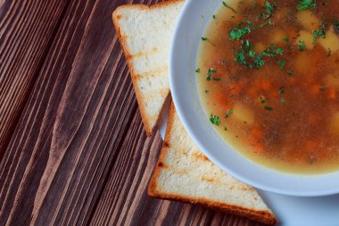 Tahta tepside ekmekle sebze çorbası. Koyu renk tahta arka planda beyaz kase. Üst Manzara. Boşluğu kopyala.
