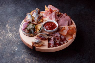 Ahşap çatal üzerinde atıştırmalıklar. Dilimlenmiş pastırma ve sosis. Bira için küçük aperatifler. Ekmek üstü balık şeklinde. Koyu dokuda yiyecek..