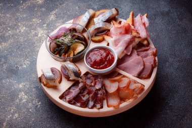 Ahşap çatal üzerinde atıştırmalıklar. Dilimlenmiş pastırma ve sosis. Bira için küçük aperatifler. Ekmek üstü balık şeklinde. Koyu dokuda yiyecek..