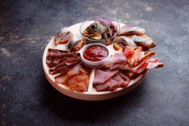 Ahşap çatal üzerinde atıştırmalıklar. Dilimlenmiş pastırma ve sosis. Bira için küçük aperatifler. Ekmek üstü balık şeklinde. Koyu dokuda yiyecek..