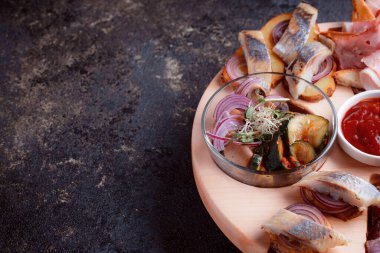 Ahşap çatal üzerinde atıştırmalıklar. Dilimlenmiş pastırma ve sosis. Bira için küçük aperatifler. Ekmek üstü balık şeklinde. Koyu dokuda yiyecek..