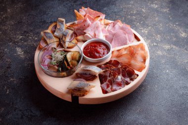 Ahşap çatal üzerinde atıştırmalıklar. Dilimlenmiş pastırma ve sosis. Bira için küçük aperatifler. Ekmek üstü balık şeklinde. Koyu dokuda yiyecek..