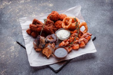 Orijinal et yemeği servisi. Kızarmış tavuk kanadı ve but. Kızarmış peynir topları, ızgara sosis, biberiye ve ketçap. Açık hava yemekleri için yiyecek..