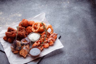 Orijinal et yemeği servisi. Kızarmış tavuk kanadı ve but. Kızarmış peynir topları, ızgara sosis, biberiye ve ketçap. Açık hava yemekleri için yiyecek..