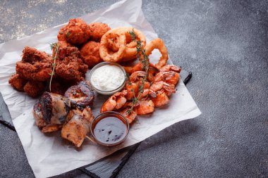 Orijinal et yemeği servisi. Kızarmış tavuk kanadı ve but. Kızarmış peynir topları, ızgara sosis, biberiye ve ketçap. Açık hava yemekleri için yiyecek..