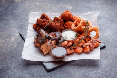 Orijinal et yemeği servisi. Kızarmış tavuk kanadı ve but. Kızarmış peynir topları, ızgara sosis, biberiye ve ketçap. Açık hava yemekleri için yiyecek..