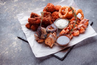 Orijinal et yemeği servisi. Kızarmış tavuk kanadı ve but. Kızarmış peynir topları, ızgara sosis, biberiye ve ketçap. Açık hava yemekleri için yiyecek..