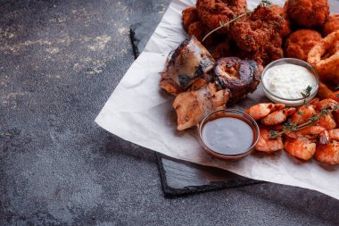 Orijinal et yemeği servisi. Kızarmış tavuk kanadı ve but. Kızarmış peynir topları, ızgara sosis, biberiye ve ketçap. Açık hava yemekleri için yiyecek..