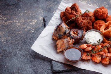 Orijinal et yemeği servisi. Kızarmış tavuk kanadı ve but. Kızarmış peynir topları, ızgara sosis, biberiye ve ketçap. Açık hava yemekleri için yiyecek..