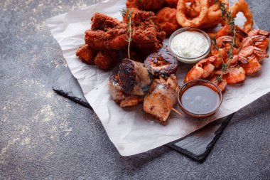 Orijinal et yemeği servisi. Kızarmış tavuk kanadı ve but. Kızarmış peynir topları, ızgara sosis, biberiye ve ketçap. Açık hava yemekleri için yiyecek..