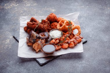 Orijinal et yemeği servisi. Kızarmış tavuk kanadı ve but. Kızarmış peynir topları, ızgara sosis, biberiye ve ketçap. Açık hava yemekleri için yiyecek..