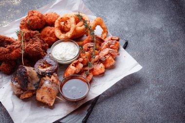 Orijinal et yemeği servisi. Kızarmış tavuk kanadı ve but. Kızarmış peynir topları, ızgara sosis, biberiye ve ketçap. Açık hava yemekleri için yiyecek..