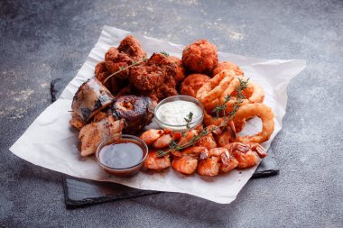 Orijinal et yemeği servisi. Kızarmış tavuk kanadı ve but. Kızarmış peynir topları, ızgara sosis, biberiye ve ketçap. Açık hava yemekleri için yiyecek..