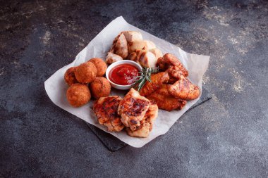 Orijinal et yemeği servisi. Kızarmış tavuk kanadı ve but. Kızarmış peynir topları, ızgara sosis, biberiye ve ketçap. Açık hava yemekleri için yiyecek..