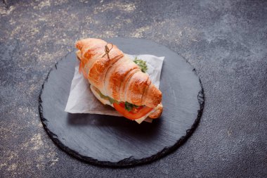 Taze lahana, kırmızı domates, prosciutto, peynir dilimi ve soğanla doldurulmuş kruvasan. Yolculuk için fast food. Benzin istasyonunda yemek hazır. Bir fırının reklamını yapmak için..