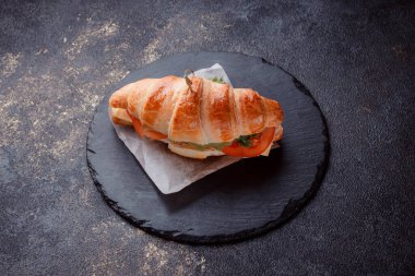 Taze lahana, kırmızı domates, prosciutto, peynir dilimi ve soğanla doldurulmuş kruvasan. Yolculuk için fast food. Benzin istasyonunda yemek hazır. Bir fırının reklamını yapmak için..
