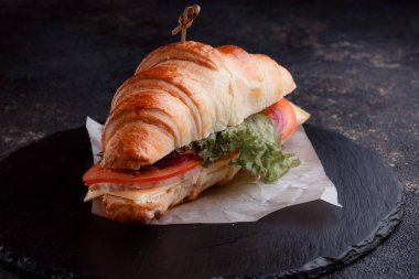 Taze lahana, kırmızı domates, prosciutto, peynir dilimi ve soğanla doldurulmuş kruvasan. Yolculuk için fast food. Benzin istasyonunda yemek hazır. Bir fırının reklamını yapmak için..