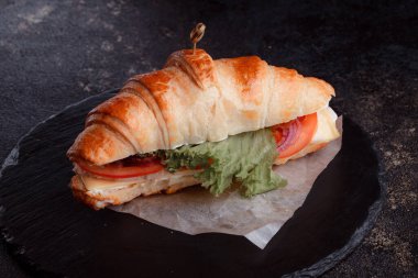 Taze lahana, kırmızı domates, prosciutto, peynir dilimi ve soğanla doldurulmuş kruvasan. Yolculuk için fast food. Benzin istasyonunda yemek hazır. Bir fırının reklamını yapmak için..