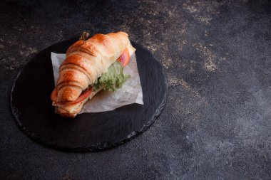 Taze lahana, kırmızı domates, prosciutto, peynir dilimi ve soğanla doldurulmuş kruvasan. Yolculuk için fast food. Benzin istasyonunda yemek hazır. Bir fırının reklamını yapmak için..