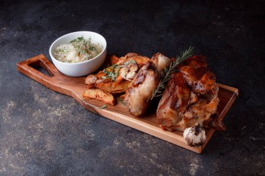 Bir set tabağı: kemiklerde büyük bir parça et, köy usulü ızgara patates, küçük bir lahana salatası, fasulye filizi, chia tohumu ve yeşil soğan. Orijinal servis ahşap kesme tahtasında..