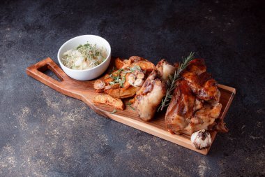 Bir set tabağı: kemiklerde büyük bir parça et, köy usulü ızgara patates, küçük bir lahana salatası, fasulye filizi, chia tohumu ve yeşil soğan. Orijinal servis ahşap kesme tahtasında..