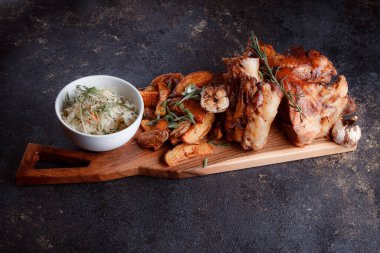 Bir set tabağı: kemiklerde büyük bir parça et, köy usulü ızgara patates, küçük bir lahana salatası, fasulye filizi, chia tohumu ve yeşil soğan. Orijinal servis ahşap kesme tahtasında..