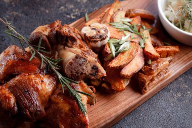 Bir set tabağı: kemiklerde büyük bir parça et, köy usulü ızgara patates, küçük bir lahana salatası, fasulye filizi, chia tohumu ve yeşil soğan. Orijinal servis ahşap kesme tahtasında..