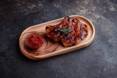 Karamelize soslu ızgara domuz bifteği. Çevre dostu ahşap kaplarda et servisi. Taze biberiye ve domates sosu..