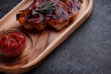 Karamelize soslu ızgara domuz bifteği. Çevre dostu ahşap kaplarda et servisi. Taze biberiye ve domates sosu..