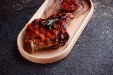 Karamelize soslu ızgara domuz bifteği. Çevre dostu ahşap kaplarda et servisi. Taze biberiye ve domates sosu..