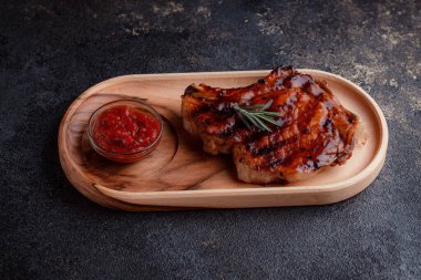 Karamelize soslu ızgara domuz bifteği. Çevre dostu ahşap kaplarda et servisi. Taze biberiye ve domates sosu..