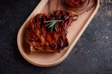 Karamelize soslu ızgara domuz bifteği. Çevre dostu ahşap kaplarda et servisi. Taze biberiye ve domates sosu..