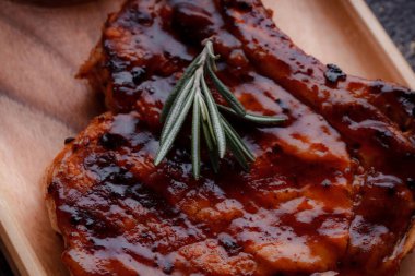 Karamelize soslu ızgara domuz bifteği. Çevre dostu ahşap kaplarda et servisi. Taze biberiye ve domates sosu..