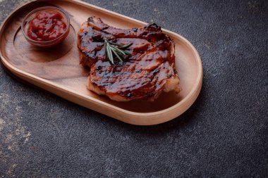 Karamelize soslu ızgara domuz bifteği. Çevre dostu ahşap kaplarda et servisi. Taze biberiye ve domates sosu..