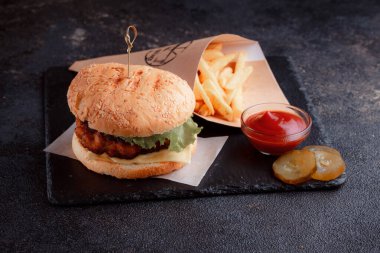 Lezzetli ev yapımı hamburger ızgara et, domates, peynir, salatalık ve ahşap masada sos..