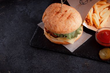 Lezzetli ev yapımı hamburger ızgara et, domates, peynir, salatalık ve ahşap masada sos..
