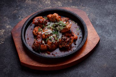 Kızarmış et ve karamelli soslu sıcak tava. Pişirilmiş ve garnitür olarak taze sebzeler. Keten tohumu ve susam tohumu eklenmiş bir yemek..