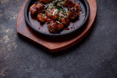 Kızarmış et ve karamelli soslu sıcak tava. Pişirilmiş ve garnitür olarak taze sebzeler. Keten tohumu ve susam tohumu eklenmiş bir yemek..