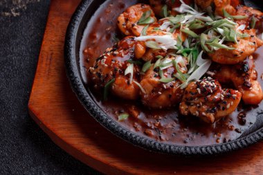 Kızarmış et ve karamelli soslu sıcak tava. Pişirilmiş ve garnitür olarak taze sebzeler. Keten tohumu ve susam tohumu eklenmiş bir yemek..