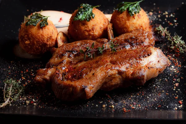 Karamelli soslu hindi bifteği ve siyah tabakta patates köftesi. Baharatlar - biber, maydanoz, fesleğen, kekik, beyaz sarımsak sosu.