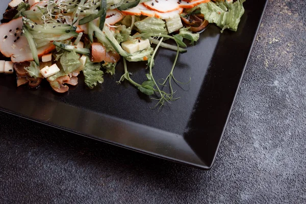 Pastırmalı yaz salatası, salatalık, peynir kübü ve mantar. Siyah tabakta yeşil salata, siyah arka planda. Bir yazı için boş yer. Yukarıdan görüntüle.