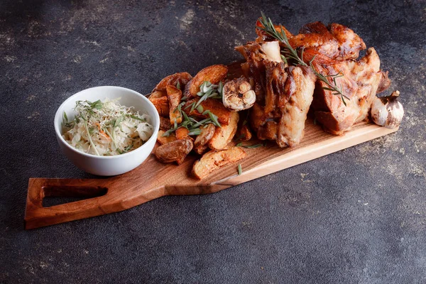 Bir set tabağı: kemiklerde büyük bir parça et, köy usulü ızgara patates, küçük bir lahana salatası, fasulye filizi, chia tohumu ve yeşil soğan. Orijinal servis ahşap kesme tahtasında..