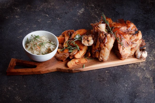 Bir set tabağı: kemiklerde büyük bir parça et, köy usulü ızgara patates, küçük bir lahana salatası, fasulye filizi, chia tohumu ve yeşil soğan. Orijinal servis ahşap kesme tahtasında..