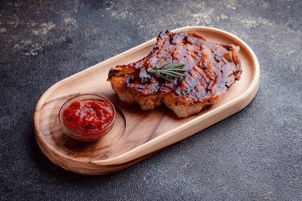 Karamelize soslu ızgara domuz bifteği. Çevre dostu ahşap kaplarda et servisi. Taze biberiye ve domates sosu..