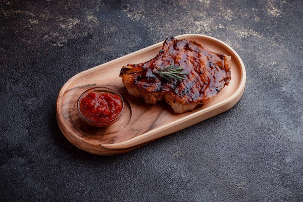 Karamelize soslu ızgara domuz bifteği. Çevre dostu ahşap kaplarda et servisi. Taze biberiye ve domates sosu..