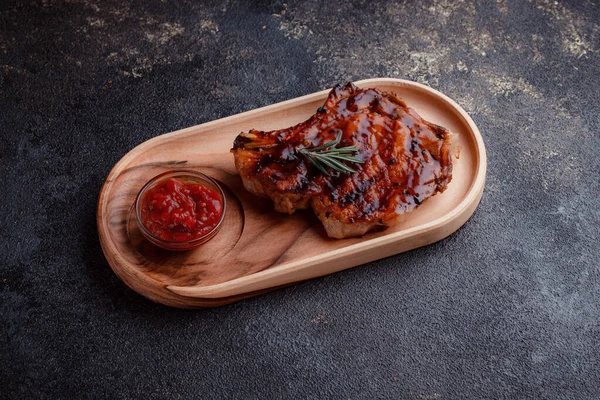 Karamelize soslu ızgara domuz bifteği. Çevre dostu ahşap kaplarda et servisi. Taze biberiye ve domates sosu..