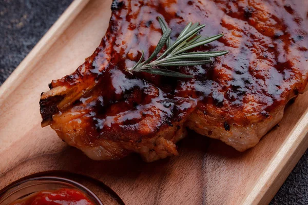 Karamelize soslu ızgara domuz bifteği. Çevre dostu ahşap kaplarda et servisi. Taze biberiye ve domates sosu..