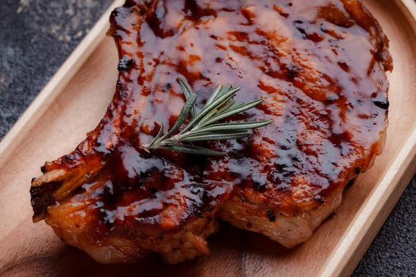 Karamelize soslu ızgara domuz bifteği. Çevre dostu ahşap kaplarda et servisi. Taze biberiye ve domates sosu..