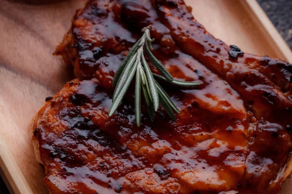 Karamelize soslu ızgara domuz bifteği. Çevre dostu ahşap kaplarda et servisi. Taze biberiye ve domates sosu..